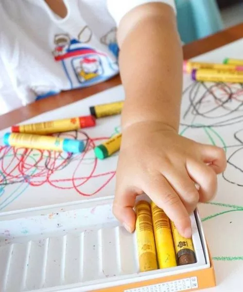 bambina prende un pennarello giallo per colorare un disegno